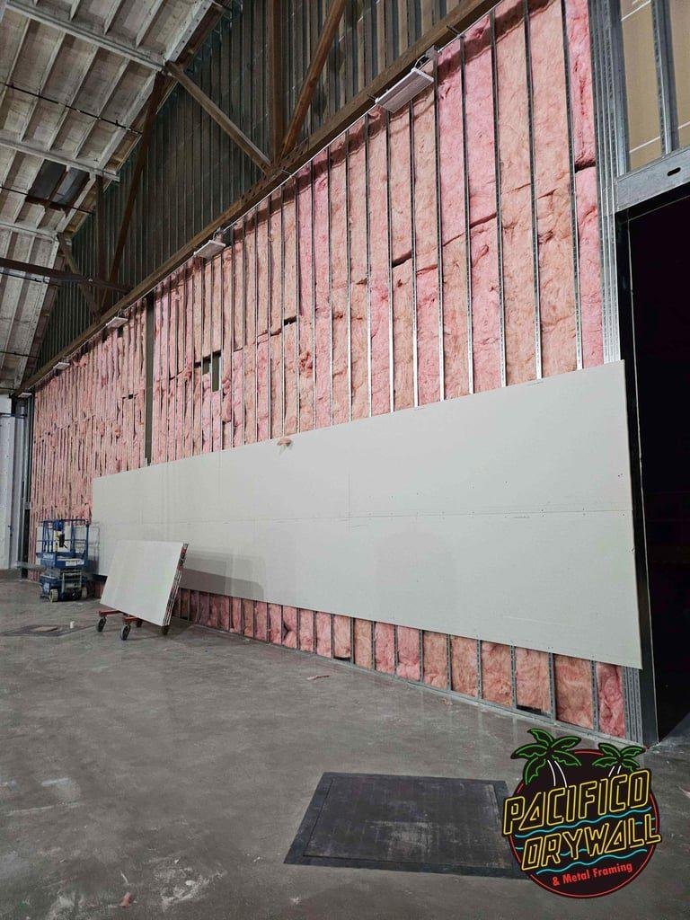Drywall installed over insulated metal framing in a warehouse